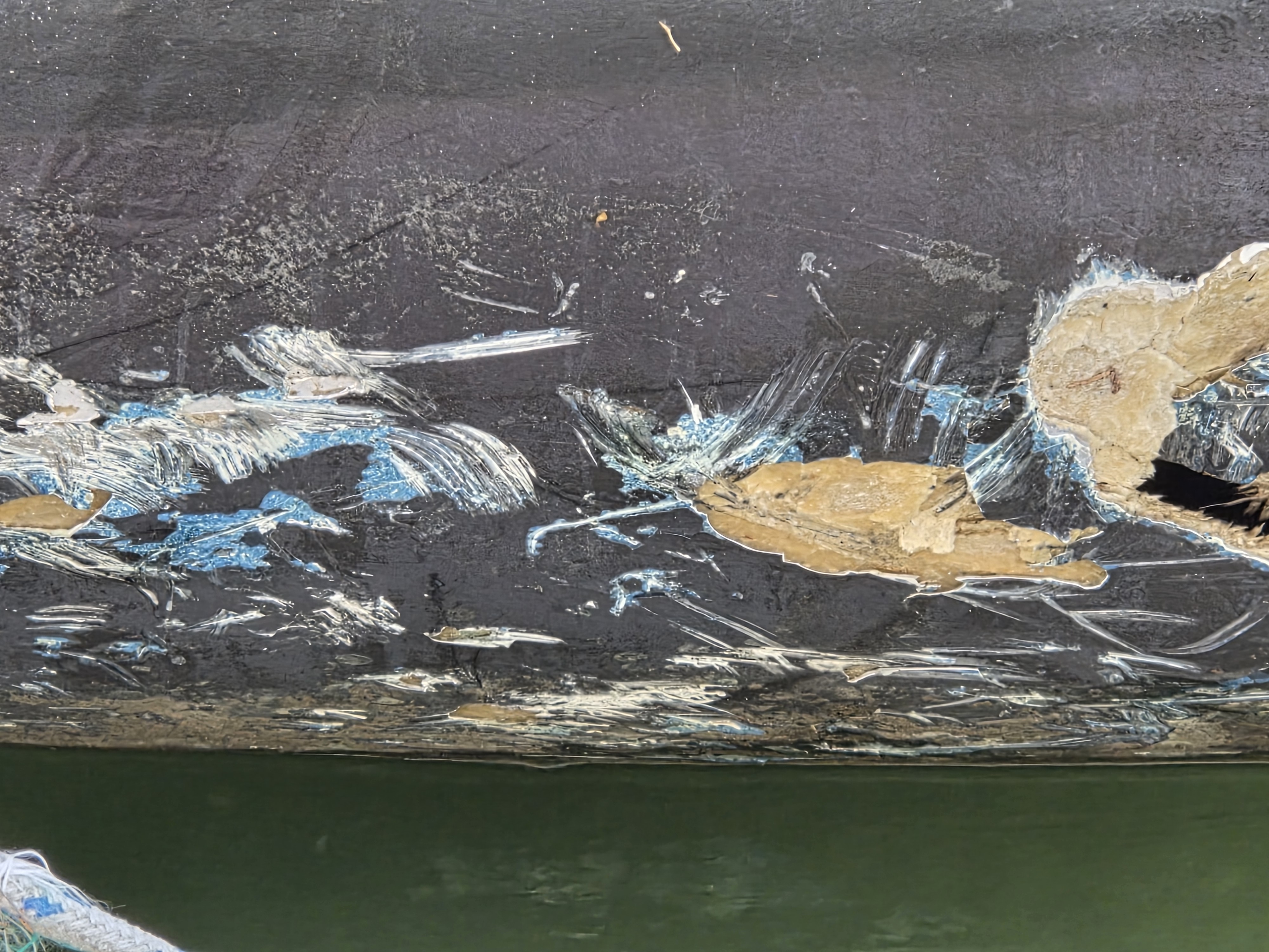 Extensive scraping damage running along the keel line for metres, antifouling stripped back to fibreglass and bare timber