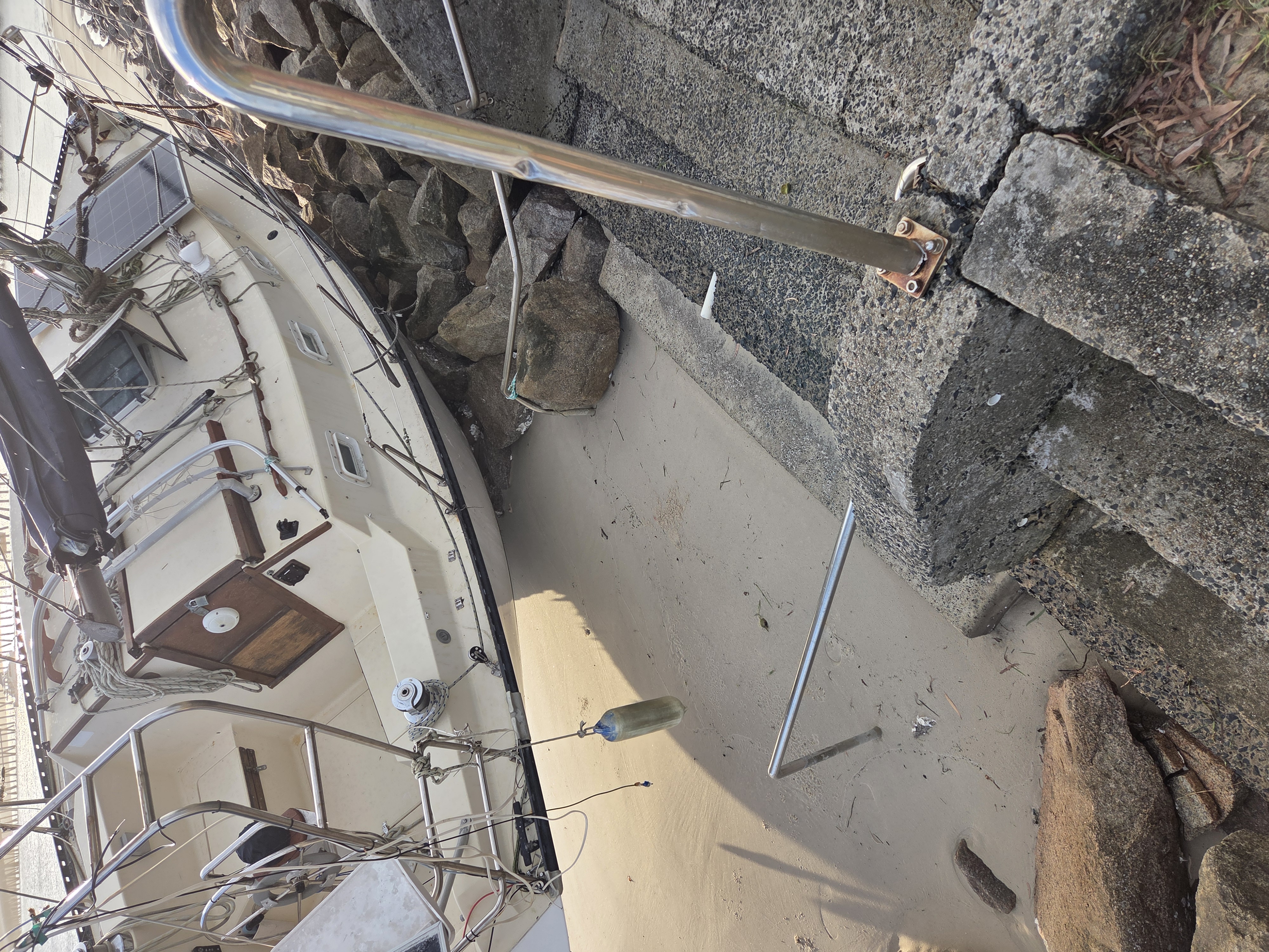 Sailing vessel listing hard against rock wall, full scale of the grounding visible